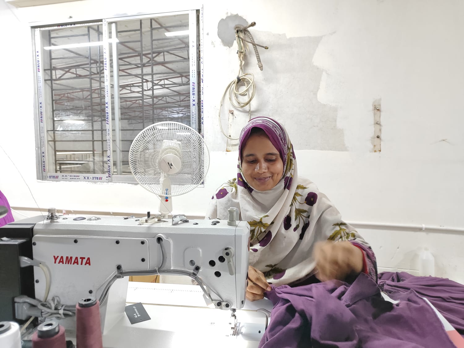 Skilled worker operating a sewing machine on the OME Sweater production floor